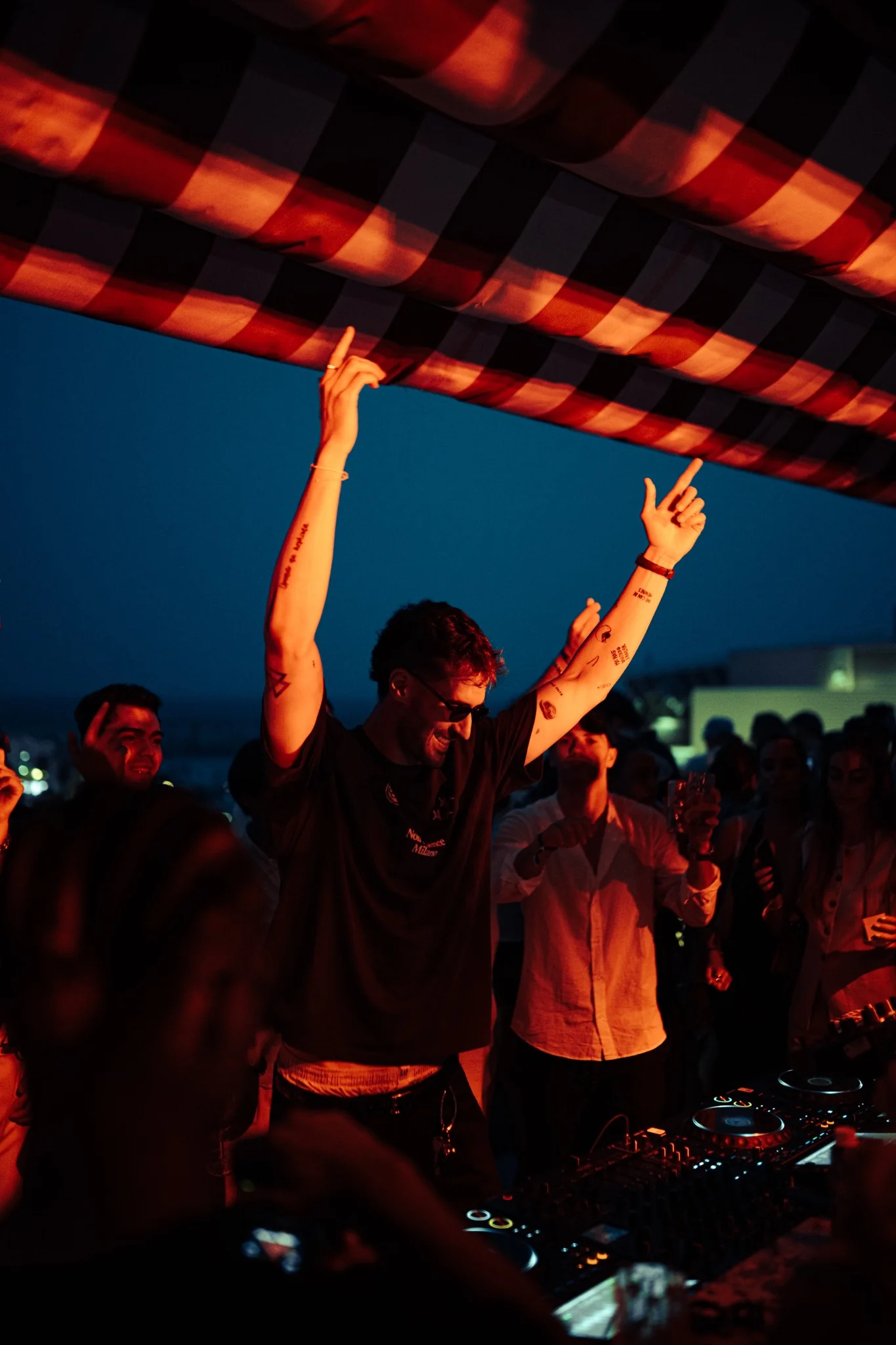LXBE raising his hands during a rooftop set